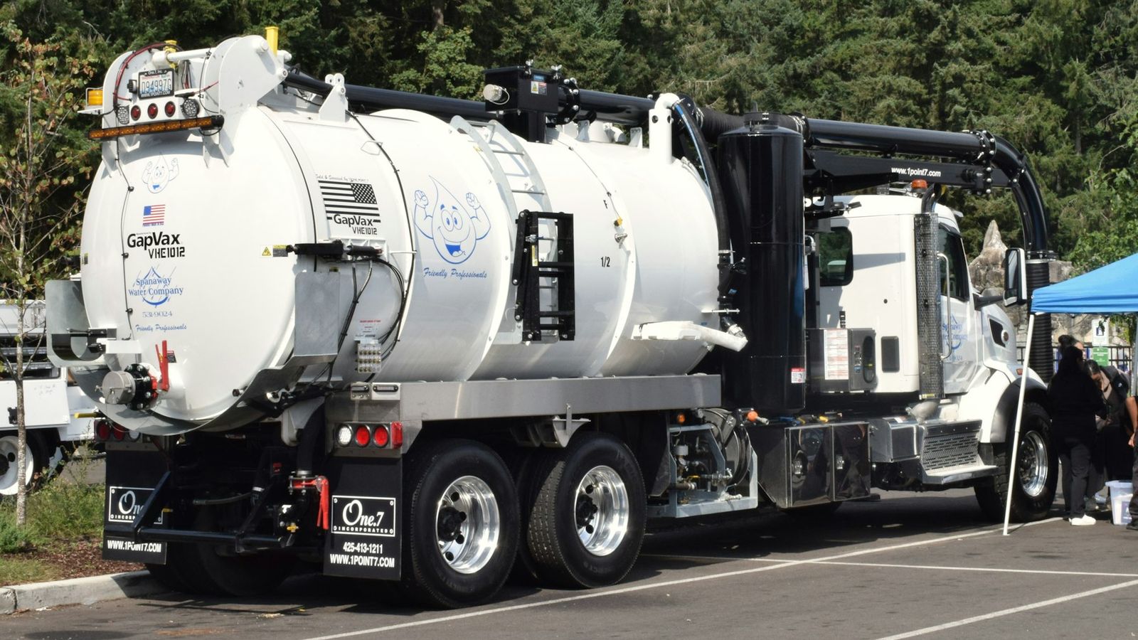A white tandem-axle vacuum truck with a large debris tank and boom parked in a lot in Washington State